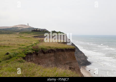 A precarious coastal path along the tops of an unstable sandy cliff. Parts of the path have clearly fallen to the beach below. Stock Photo