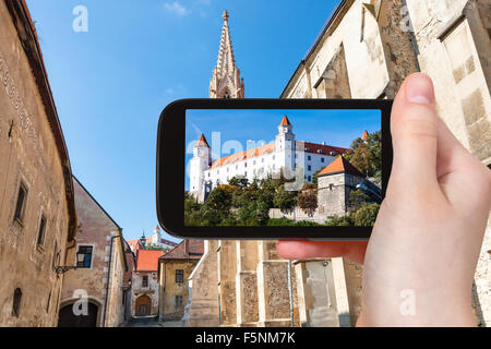 travel concept - tourist snapshot of Bratislava Hrad castle from Farska street in old town on smartphone Stock Photo