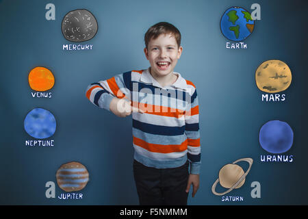 Teen boy points his finger down and laughs planets of the solar Stock Photo