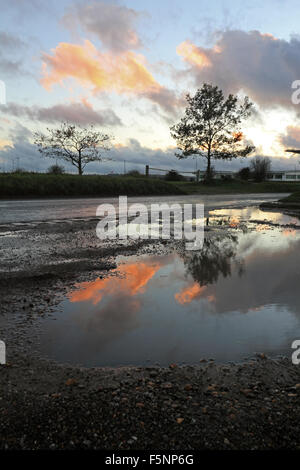 Epsom Downs, Surrey. 7th November 2015. After a day of wind and rain the storm finally passed just before dusk at Epsom Downs Surrey. The warm glow of the setting sun reflected in the huge puddles in the car park behind the grandstand. Credit:  Julia Gavin UK/Alamy Live News Stock Photo