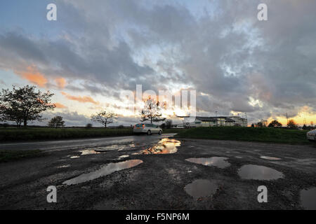 Epsom Downs, Surrey. 7th November 2015. After a day of wind and rain the storm finally passed just before dusk at Epsom Downs Surrey. The warm glow of the setting sun reflected in the huge puddles in the car park behind the grandstand. Credit:  Julia Gavin UK/Alamy Live News Stock Photo