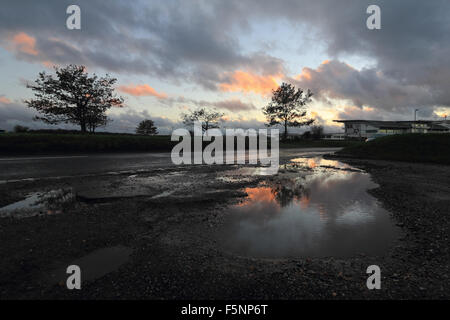 Epsom Downs, Surrey. 7th November 2015. After a day of wind and rain the storm finally passed just before dusk at Epsom Downs Surrey. The warm glow of the setting sun reflected in the huge puddles in the car park behind the grandstand. Credit:  Julia Gavin UK/Alamy Live News Stock Photo