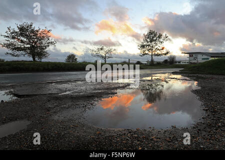 Epsom Downs, Surrey. 7th November 2015. After a day of wind and rain the storm finally passed just before dusk at Epsom Downs Surrey. The warm glow of the setting sun reflected in the huge puddles in the car park behind the grandstand. Credit:  Julia Gavin UK/Alamy Live News Stock Photo