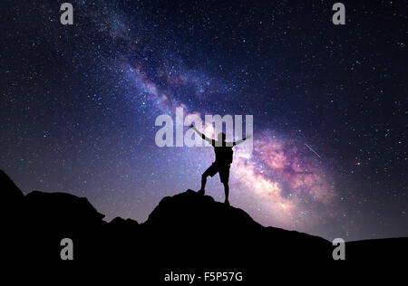 Milky Way. Night sky with stars and silhouette of a man with raised-up arms. Stock Photo