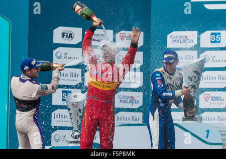 Lucas di Grassi, Sam Bird, and Robin Frijns spray champagne on the winners' podium after the 2015 Malaysian ePrix in Putrajaya. Stock Photo