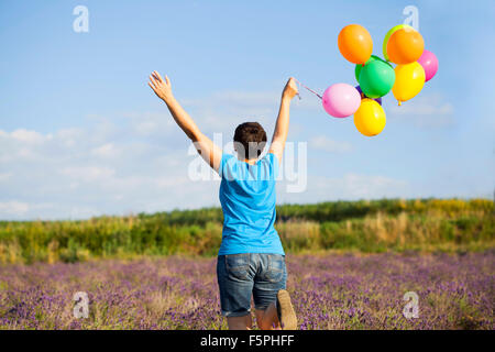 Vintage photo of young woman with colorful balloons in the summer field Stock Photo