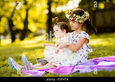 Little girl and baby sitting in the grass Stock Photo