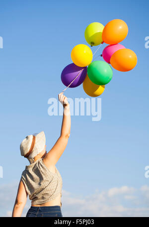 Vintage photo of young woman with colorful balloons in the summer field Stock Photo