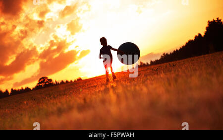 Little man playing football on the meadow Stock Photo