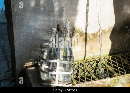 Vintage bottles being refilled by local at water outlet at Alet les Bains springs.Therapeutic qualities, fresh free natural eau. Stock Photo