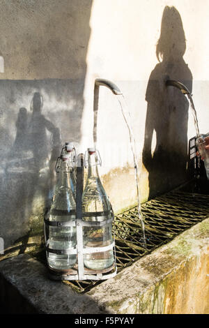 Vintage bottles being refilled by local at water outlet at Alet les Bains springs.Therapeutic qualities, fresh free natural eau. Stock Photo