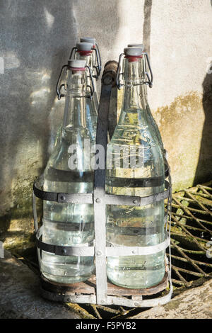 Vintage bottles being refilled by local at water outlet at Alet les Bains springs.Therapeutic qualities, fresh free natural eau. Stock Photo