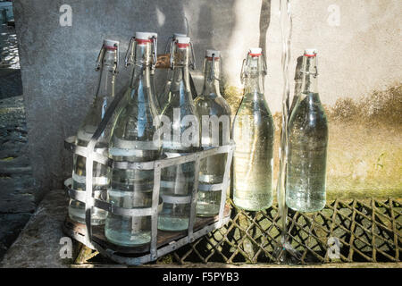 Vintage bottles being refilled by local at water outlet at Alet les Bains springs.Therapeutic qualities, fresh free natural eau. Stock Photo