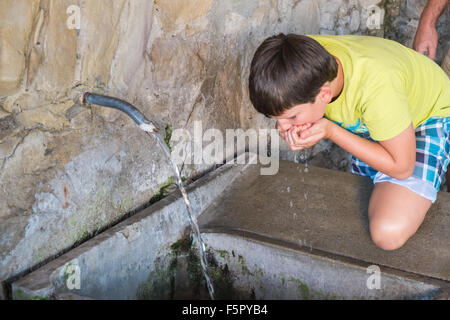 Boy drinking fresh spring water at water outlet at Alet les Bains springs.Therapeutic qualities, fresh free natural eau. Stock Photo