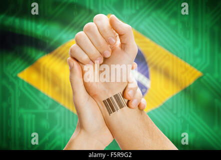 Barcode ID number on wrist of a human and national flag on background - Brazil Stock Photo