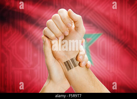 Barcode ID number on wrist of a human and national flag on background - Morocco Stock Photo