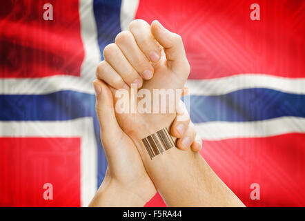 Barcode ID number on wrist of a human and national flag on background - Norway Stock Photo
