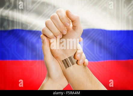 Barcode ID number on wrist of a human and national flag on background - Russia Stock Photo