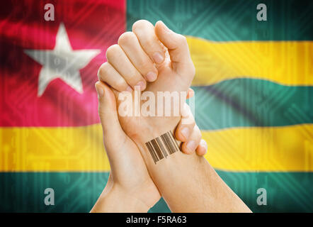 Barcode ID number on wrist of a human and national flag on background - Togo Stock Photo