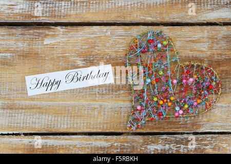 Happy Birthday card with heart made of colorful beads on rustic wooden surface Stock Photo