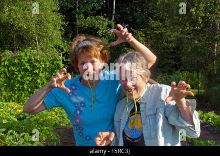 Two women demonstrate the funny and side of gardening wearing green bean fangs amd joking in friendship, Yarmouth Maine, USA Stock Photo