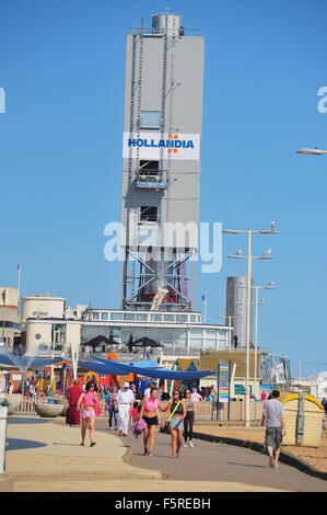 Pedestrians walk along the Brighton seafront with the i360 observation tower construction site visible in the background. Stock Photo