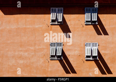 Four shuttered windows casting long shadows in the old town in Nice France Stock Photo