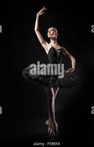 Slim ballerina in a black corset and black tutu. Rehearsal in the theater. Classical Ballet. Stock Photo
