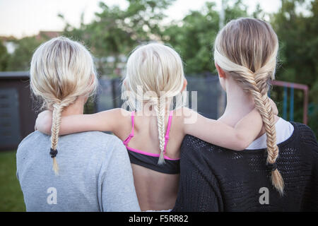 Sweden, Vastergotland, Lerum, Rear view of girls (8-9, 16-17) with braided ponytail standing in backyard