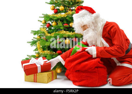 Nice Santa putting gift boxes under the Christmas tree, studio isolated Stock Photo