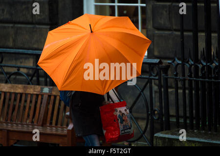 Edinburgh, Scotland, UK. 09th Nov, 2015. Monday 9th of November 2015: Weather - Edinburgh. A pedestrian with a bright orange umbrella on the Royal Mile in Edinburgh this morning. Gale force winds are expected to hit the UK today which could see the first naming of a storm under the new system. If the weather is severe as forecasters predict and meets storm criteria then the Met Office will officially name it Storm Abigail Credit:  Andrew O'Brien/Alamy Live News Stock Photo