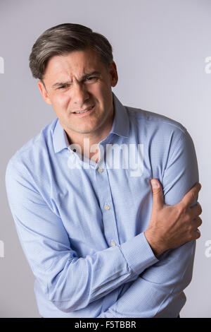 Studio Of Mature Man Clutching Arm As Warning Of Heart Attack Stock Photo