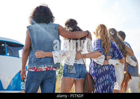 young hippie friends hugging over minivan car Stock Photo