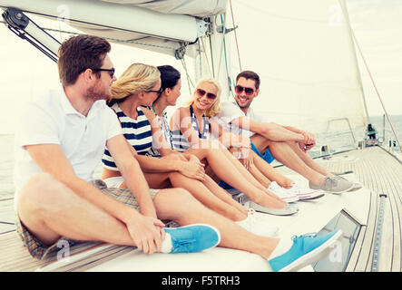 smiling friends sitting on yacht deck Stock Photo