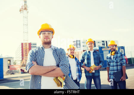 group of smiling builders in hardhats outdoors Stock Photo