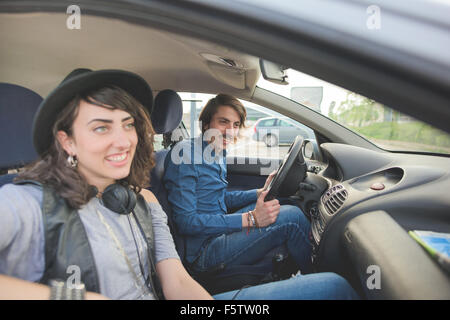 Couple of young handsome man and woman driving a car, having fun, overlooking right, smiling - relaxing, happiness concept Stock Photo