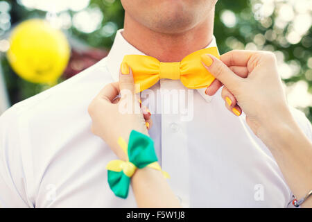 female hand man corrects a yellow bow tie Stock Photo