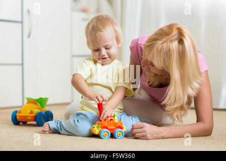 Child boy and his mother repair toy car at home Stock Photo