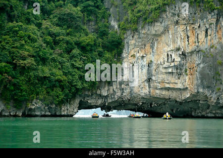 Tourists on wooden row boats and limestone (karst) cave, Vung Vieng fishing village, Ha Long Bay, Bai Tu Long Sector, Vietnam Stock Photo