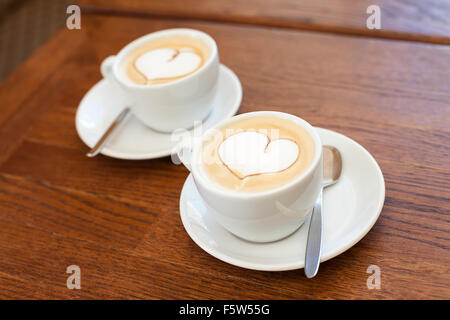 two cups of coffee on a table with a foam heart shape Stock Photo