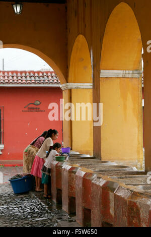 Guatemalan women wash laundry in a traditional street washing facility in Antigua, Guatemala Stock Photo