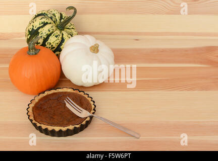 Three mini pumpkins with small pumpkin pie and fork on a wooden table, with copy space Stock Photo