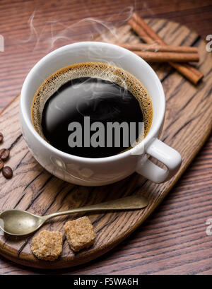 Cup of coffee and cane sugar cubes on wooden table. Stock Photo