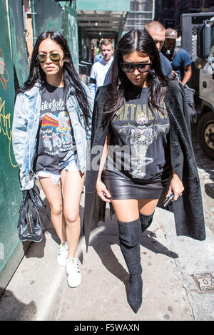 Kim Kardashian wearing a long black coat black knee high boots and a Metallica t shirt