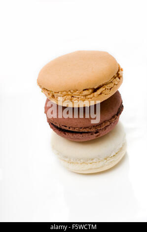 Vanilla, Chocolate, and Salted Caramel macaroons stacked on white ceramic. Stock Photo