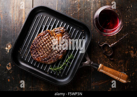 Grilled Black Angus Steak Ribeye on grill pan and red wine on wooden background Stock Photo