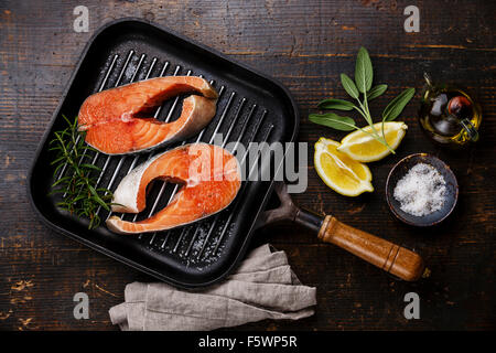 Raw salmon Steak on grill pan on wooden background with seasoning Stock Photo