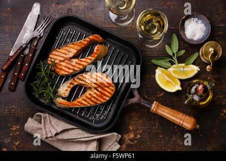 Grilled salmon Steak on grill pan on wooden background with wine Stock Photo