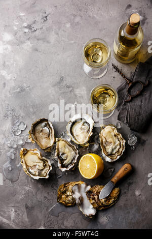 Opened Oysters Fines de Claire and white wine on gray concrete texture background Stock Photo