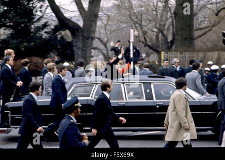Washington, DC. USA 20th January 1981 President Ronald Reagan and First Lady Nancy Reagan wave to the crowds lining the inaugural parade route from the sun roof of their limousine. Their detail of Secret Service agents walk  along side the limousine as they leave the US Capitol grounds en route to the White House. Stock Photo